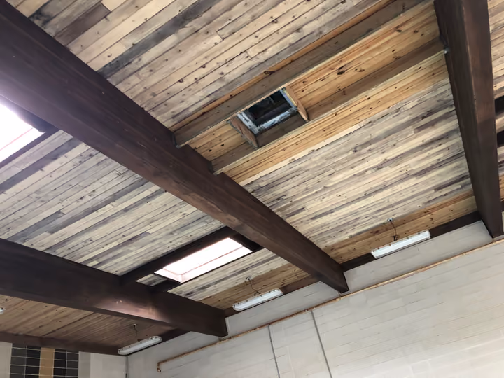 New linear LED fixtures running between the dark wooden beams of the Mission Clubhouse ceiling