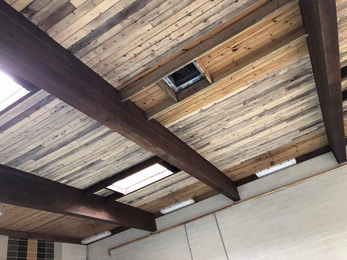 New linear LED fixtures running between the dark wooden beams of the Mission Clubhouse ceiling