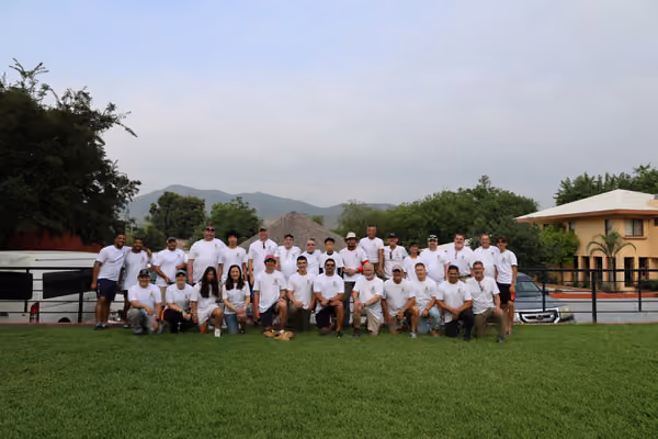The Utilicast volunteer team, around forty people in white shirts, gathered on the lawn at the Back2Back Ministries site